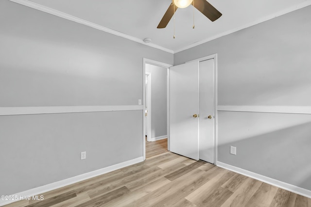 unfurnished bedroom with wood finished floors, a closet, ornamental molding, ceiling fan, and baseboards