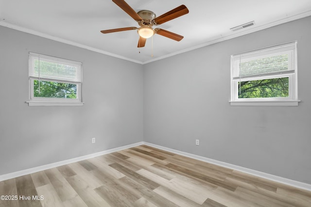 empty room with ornamental molding, light wood finished floors, visible vents, and a healthy amount of sunlight