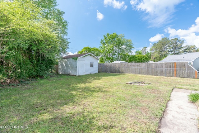 view of yard with an outdoor structure, a storage shed, and a fenced backyard