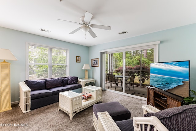 living area featuring visible vents, a wealth of natural light, and carpet flooring