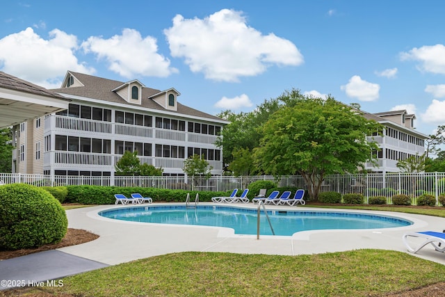 community pool with fence, a patio area, a yard, and a sunroom