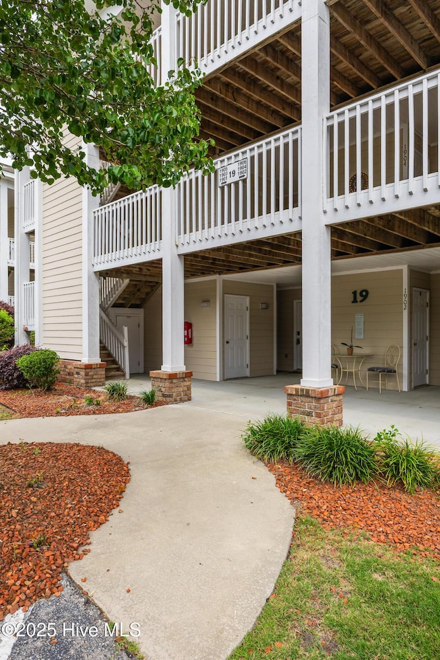 exterior space featuring a carport, concrete driveway, and stairs
