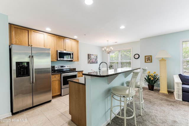 kitchen with appliances with stainless steel finishes, a kitchen bar, plenty of natural light, and a notable chandelier