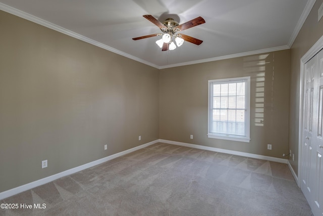 spare room with crown molding, a ceiling fan, baseboards, and light carpet