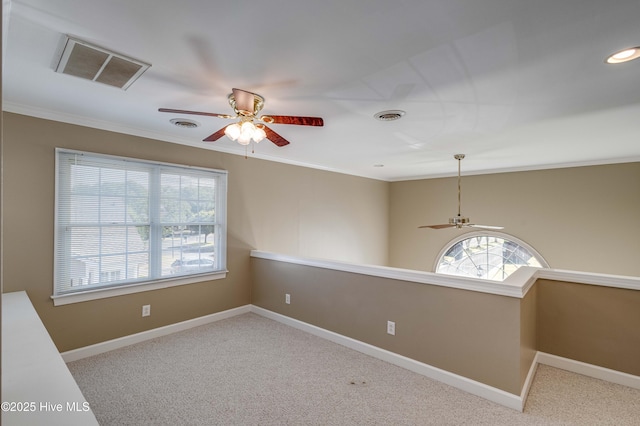 spare room featuring crown molding, a ceiling fan, visible vents, and a wealth of natural light