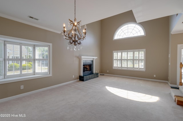 unfurnished living room featuring visible vents, a tile fireplace, a notable chandelier, ornamental molding, and carpet flooring