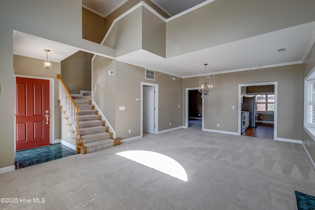 carpeted entryway featuring baseboards, visible vents, ornamental molding, and a chandelier