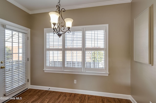 unfurnished dining area featuring baseboards, a chandelier, ornamental molding, and dark wood-type flooring