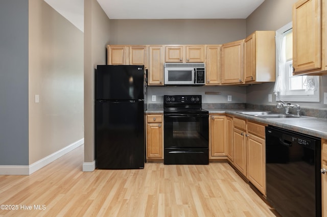 kitchen with black appliances, light brown cabinets, light wood finished floors, and a sink