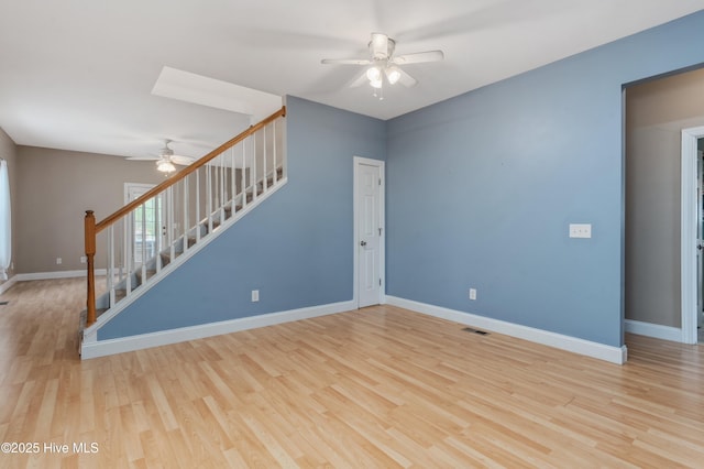 unfurnished living room featuring stairway, ceiling fan, visible vents, baseboards, and wood finished floors