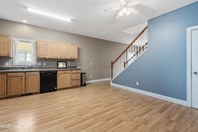 kitchen with a sink, light wood-style floors, black dishwasher, baseboards, and dark countertops