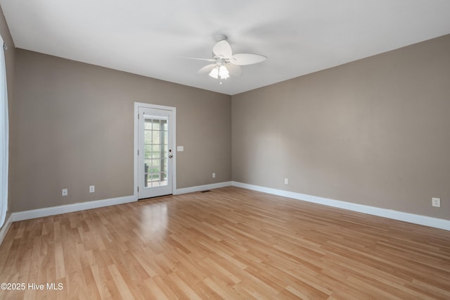 spare room featuring light wood-type flooring, a ceiling fan, and baseboards