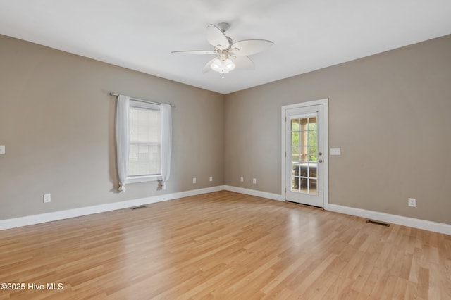empty room featuring a ceiling fan, visible vents, baseboards, and light wood-style floors
