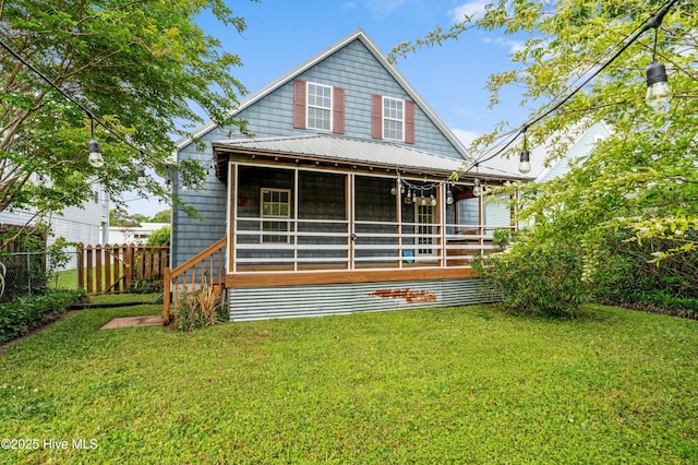 rear view of house featuring fence, a lawn, and a sunroom