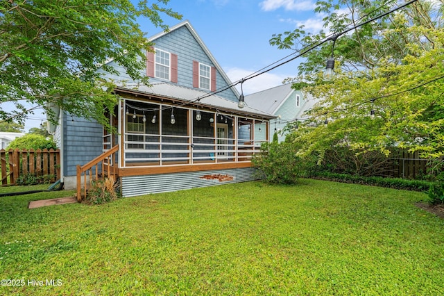 back of house featuring fence, a yard, and a sunroom