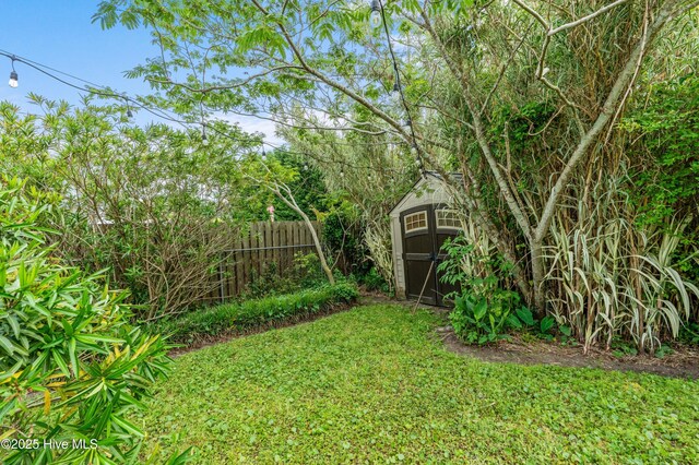 view of yard with fence, a storage shed, and an outbuilding