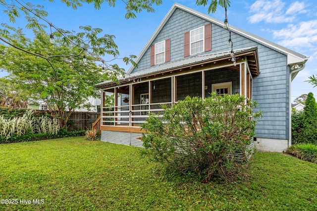 rear view of property featuring fence, a sunroom, and a lawn