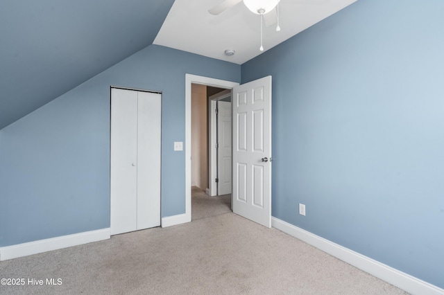 unfurnished bedroom with baseboards, a closet, lofted ceiling, and carpet