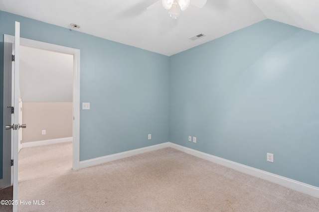 empty room featuring visible vents, carpet, and vaulted ceiling