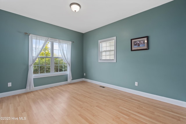 empty room featuring wood finished floors, visible vents, and baseboards