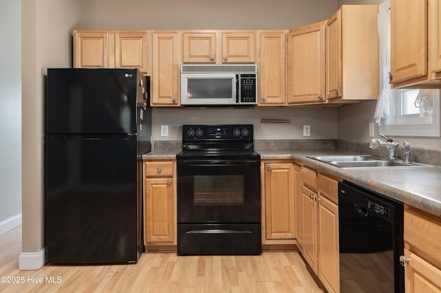 kitchen featuring black appliances, light brown cabinets, light wood finished floors, and a sink