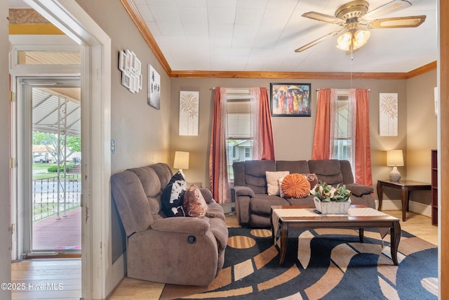 living area with light wood-type flooring, a ceiling fan, and crown molding