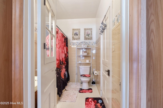 bathroom with tile walls, tile patterned floors, and toilet