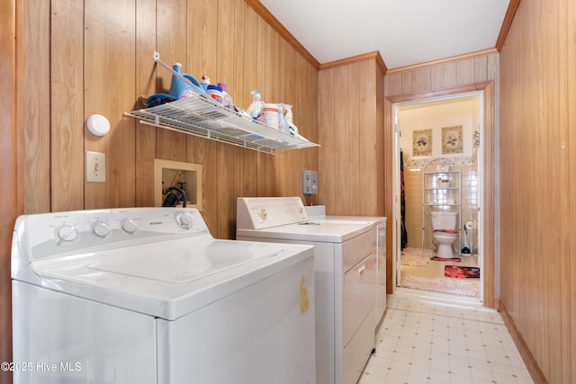 laundry room featuring light floors, laundry area, washing machine and dryer, wooden walls, and crown molding
