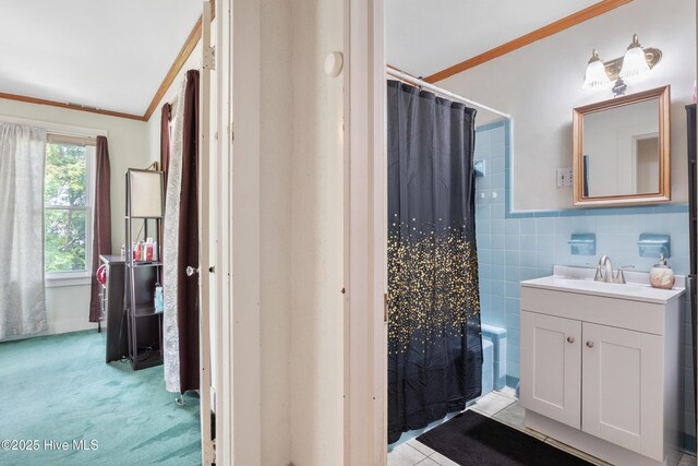 full bathroom with ornamental molding, tile walls, shower / bathtub combination with curtain, vanity, and wainscoting