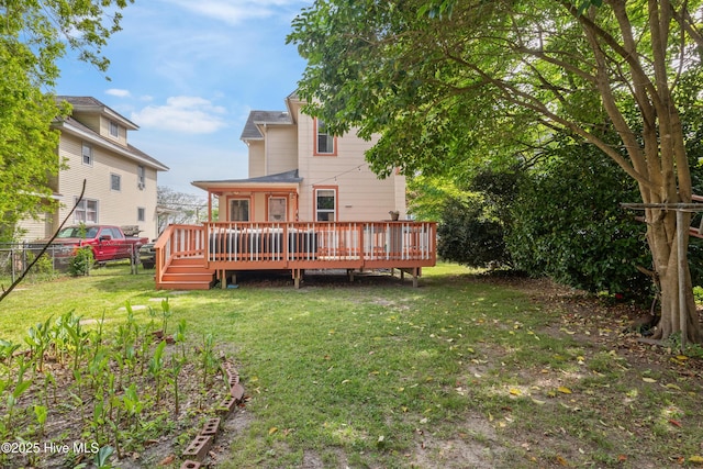 rear view of property featuring fence, a deck, and a lawn
