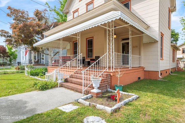view of front of home featuring covered porch, a front yard, and crawl space
