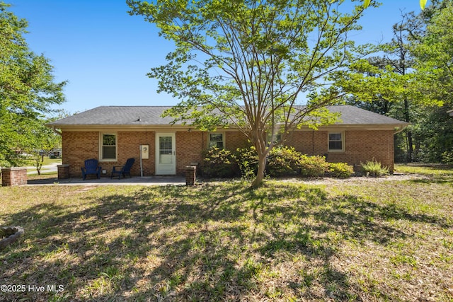 rear view of property featuring a lawn, brick siding, and a patio area