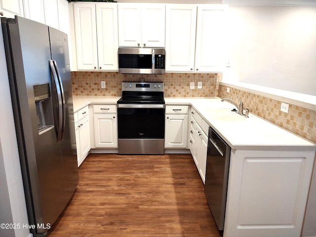 kitchen featuring appliances with stainless steel finishes, tasteful backsplash, a sink, white cabinets, and dark wood-style floors