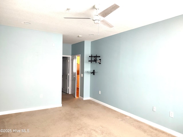 carpeted spare room with baseboards and a ceiling fan