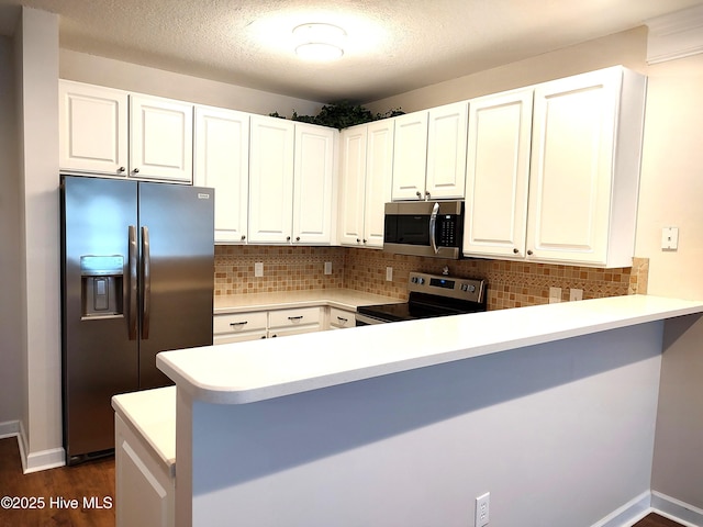 kitchen featuring a peninsula, light countertops, white cabinets, tasteful backsplash, and stainless steel appliances