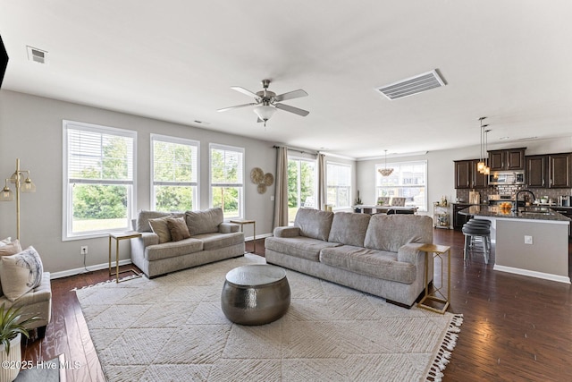 living area featuring visible vents, a ceiling fan, baseboards, and dark wood-style flooring