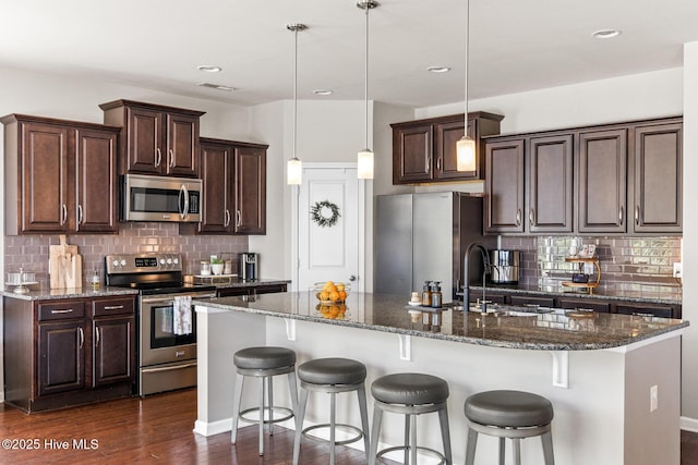 kitchen with stainless steel appliances, a sink, dark wood-type flooring, and tasteful backsplash