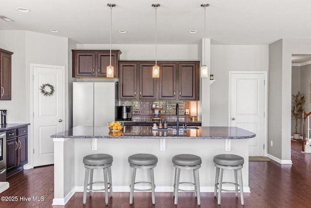 kitchen with visible vents, dark brown cabinets, freestanding refrigerator, dark wood-type flooring, and an island with sink
