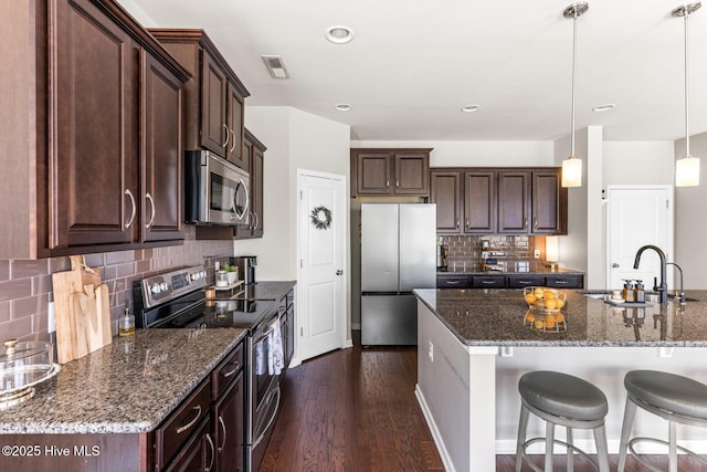 kitchen featuring a sink, tasteful backsplash, stainless steel appliances, and dark brown cabinets