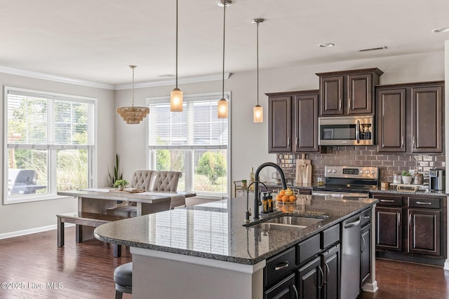 7408 Darius Dr, Wilmington, NC 28411 - kitchen with appliances with stainless steel finishes, a sink, dark wood-style floors, tasteful backsplash, and a breakfast bar