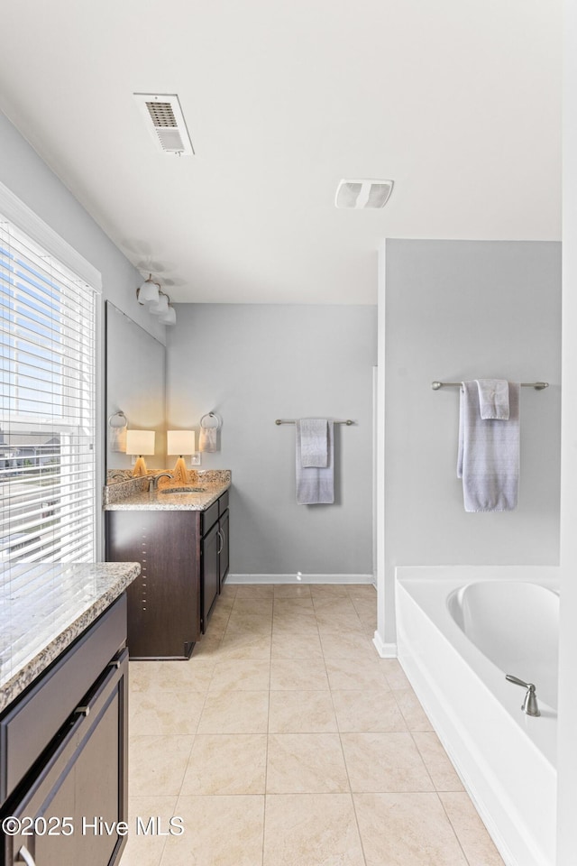 full bathroom with tile patterned flooring, visible vents, a garden tub, and vanity