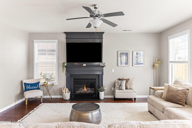 living area with a healthy amount of sunlight, a fireplace with flush hearth, baseboards, and wood finished floors