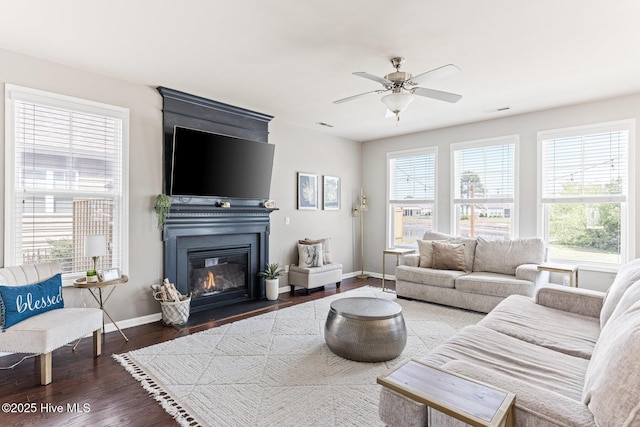living area featuring baseboards, ceiling fan, wood finished floors, and a healthy amount of sunlight