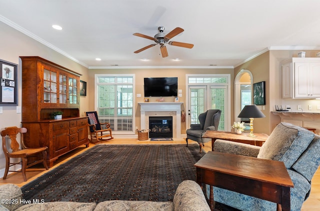3603 Seafoam Ct, New Bern, NC 28562 - living room featuring wood finished floors, a glass covered fireplace, a ceiling fan, plenty of natural light, and crown molding