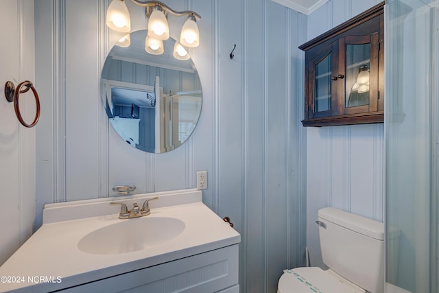 half bath featuring crown molding, vanity, toilet, and a decorative wall