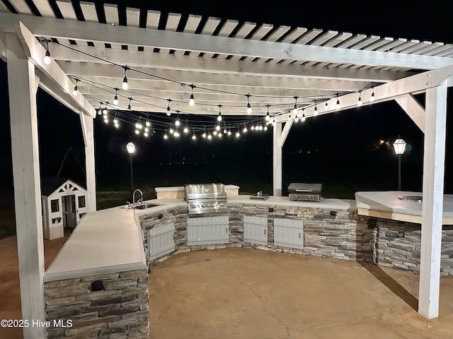 204 Liana Pl, Hubert, NC 28539 - patio at night with grilling area, exterior kitchen, a sink, and a pergola