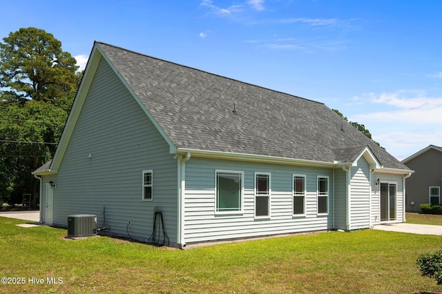 view of home's exterior with central air condition unit, a lawn, and roof with shingles