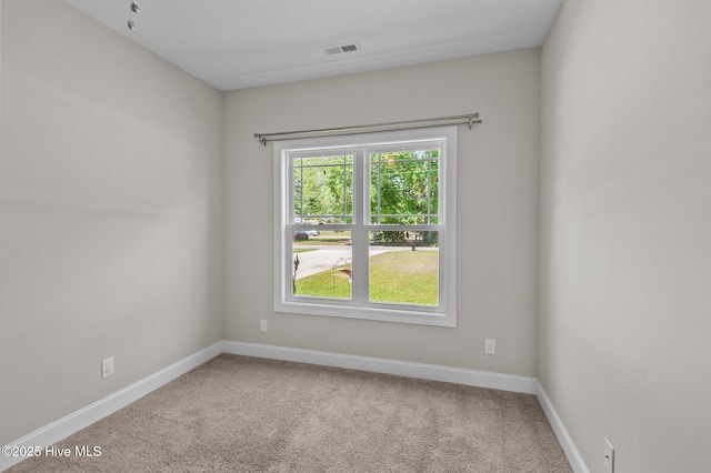 carpeted spare room featuring baseboards and visible vents