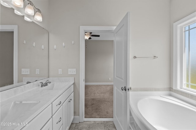 full bathroom featuring a garden tub, a ceiling fan, double vanity, baseboards, and a sink