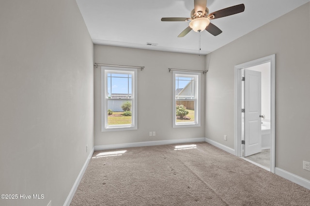 spare room with light colored carpet, baseboards, ceiling fan, and visible vents
